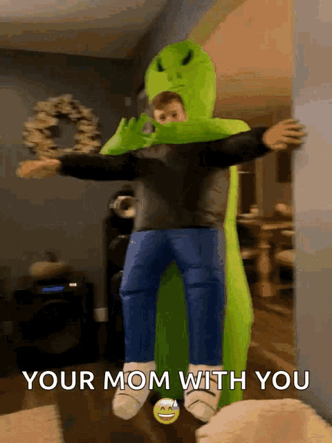 a child in a green alien costume is hugging another child