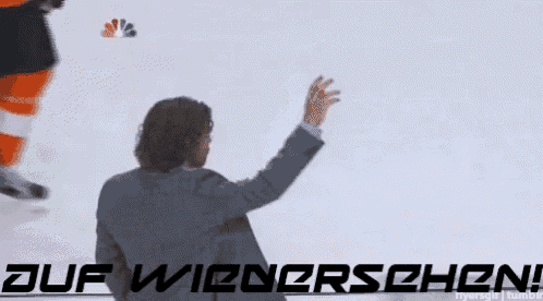 a man in a suit waves his hand in front of a sign that says ' auf wienrschen '