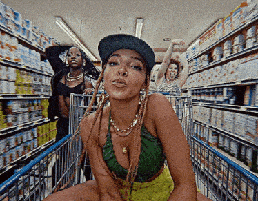 a woman is sitting in a shopping cart in a grocery store with other women .