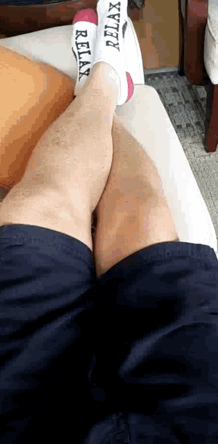 a person laying on a bed with a pair of socks that say relax