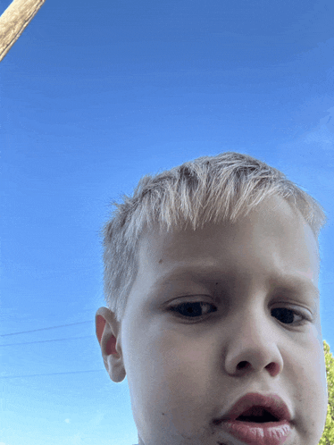 a young boy with a blue sky behind him