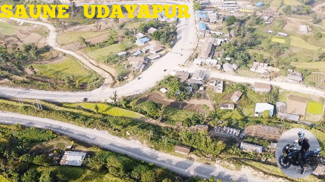 an aerial view of saune udayapur with a person riding a motorcycle in the foreground