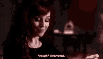 a woman is holding her chest in a dark room while talking .