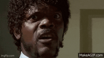 a man with curly hair and a beard is looking at the camera with a surprised look on his face .