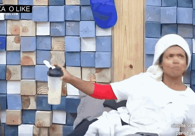 a person holding a shaker in front of a wooden wall that says ka o like on it