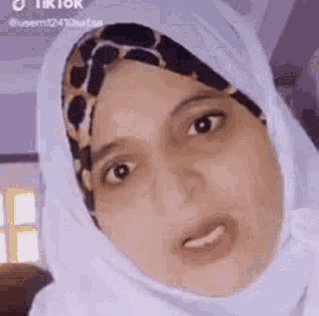 a woman wearing a hijab is making a funny face and making a funny face .