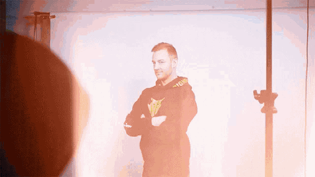 a man wearing a black hoodie with a yellow logo on the front