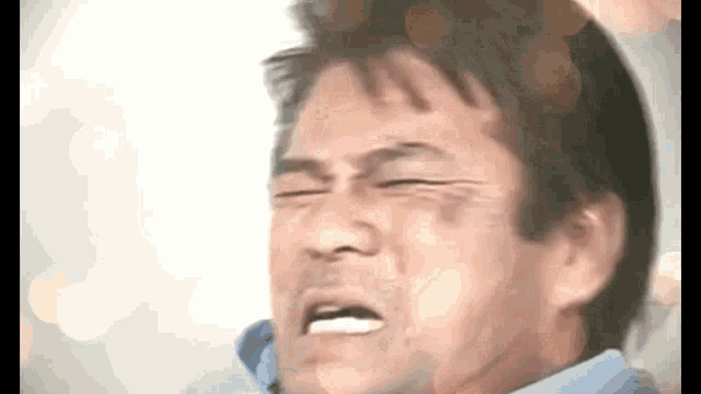 a man in a blue shirt is making a funny face with his mouth open .