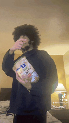 a man holding a bag of ritz specials covering his face