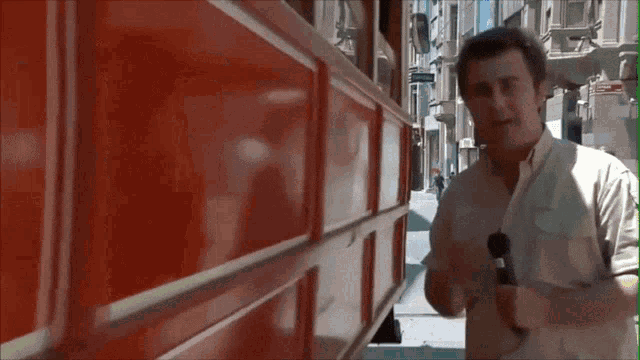 a man in a white shirt stands in front of a red building