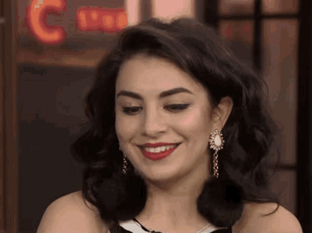 a close up of a woman wearing earrings and red lipstick smiling .
