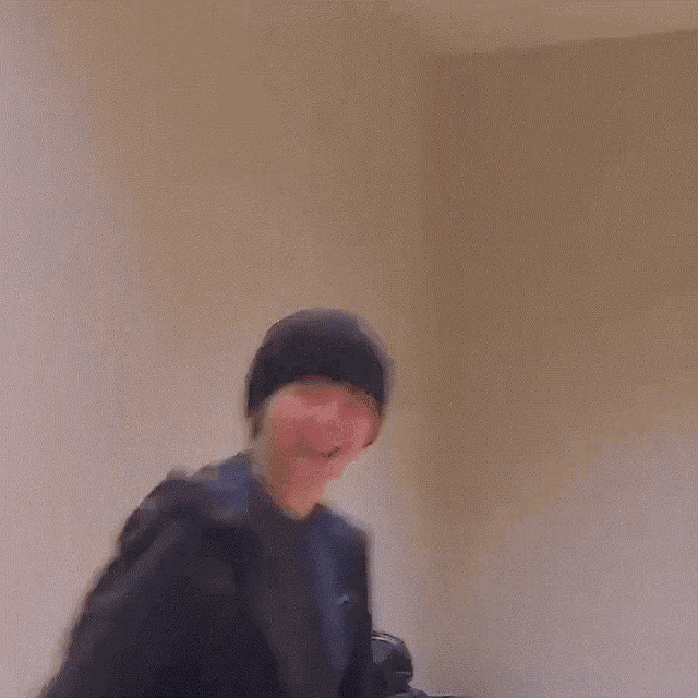 a man wearing a black beanie and a black jacket is standing in a room .
