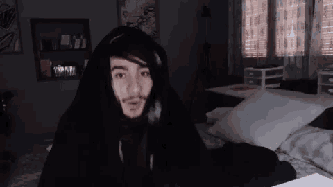 a man is sitting on a bed wearing headphones and a hoodie .