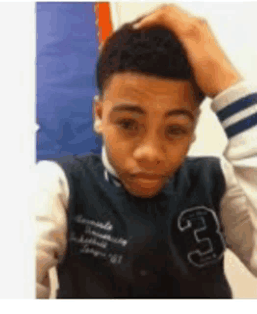 a young man in a varsity jacket is taking a selfie .