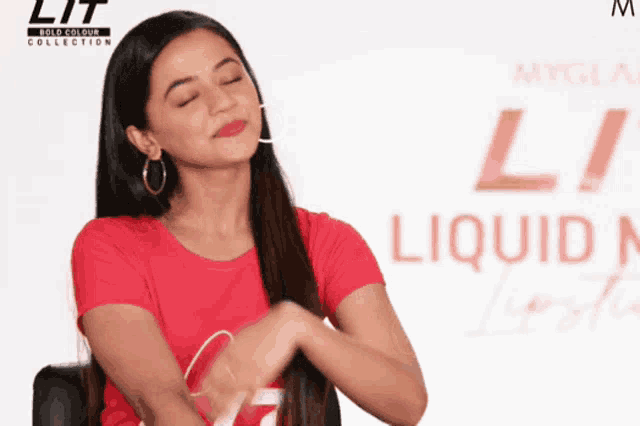 a woman in a red shirt is standing in front of a sign that says liquid