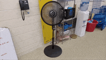 a fan is sitting next to a water cooler that says aquafina on it
