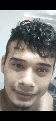 a close up of a man 's face with curly hair and a beard smiling .