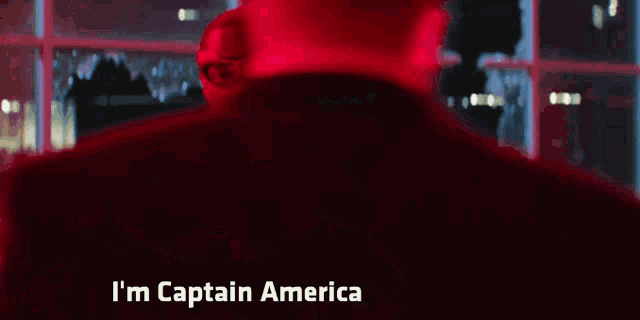 a man in a red costume says i 'm captain america in front of a window