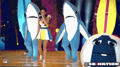 a woman in a dress is surrounded by shark costumes and a sb nation logo
