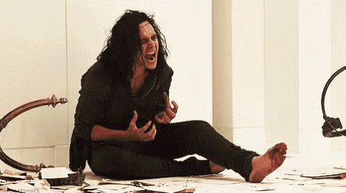 a man with long hair is sitting on the floor with his feet in the blood and screaming .