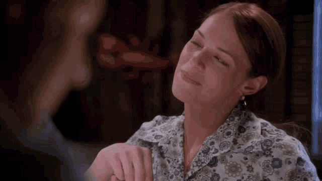 a woman wearing a floral shirt is smiling and looking at a man