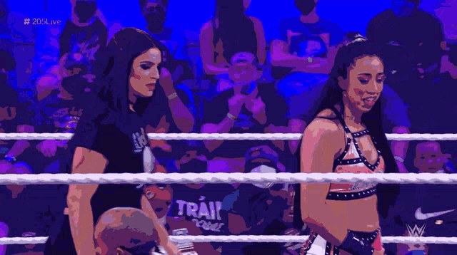 two women are standing in a wrestling ring with the hashtag # 20live on the bottom