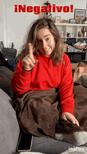 a woman in a red sweater is giving a thumbs up in front of a sign that says negative