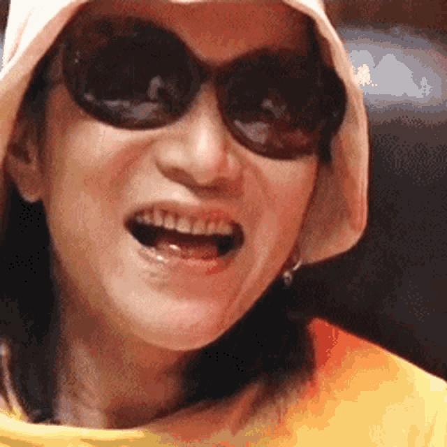 a woman wearing sunglasses and a hat is smiling