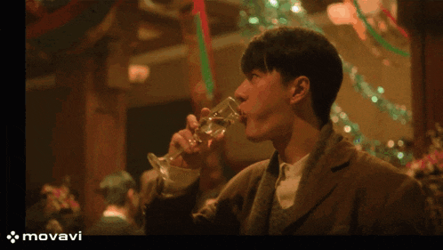 a man is drinking from a glass with the word movavi on the bottom