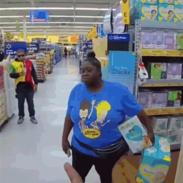 a woman wearing a beavis and butthead shirt is walking down a store hallway