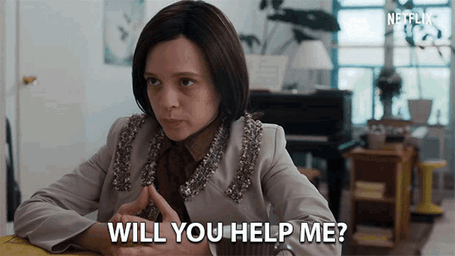 a woman is sitting at a table and asking " will you help me " .