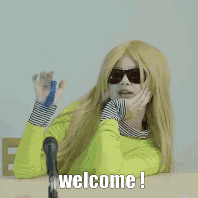 a blonde woman wearing sunglasses and a neon green shirt says welcome