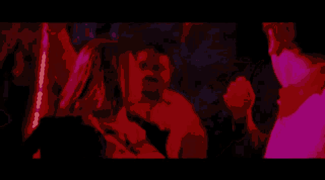 a group of people dancing in a dark room with red lights .