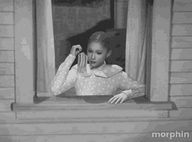 a black and white photo of a woman looking out a window with the word morphin on the bottom right