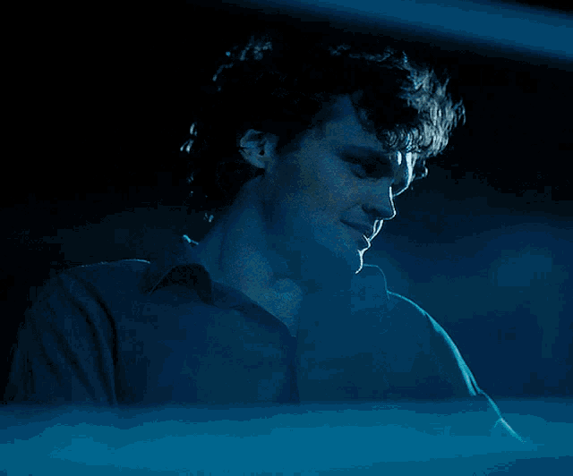 a man in a blue shirt looks down at something