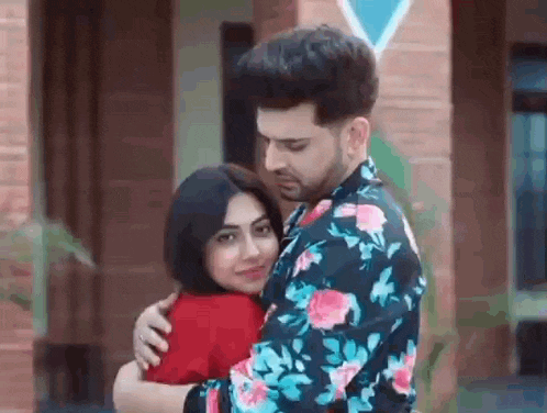 a man is hugging a woman in front of a brick building .