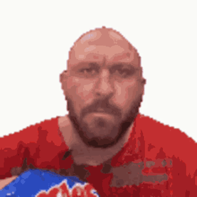 a bald man with a beard and a red shirt is holding a boxing glove .
