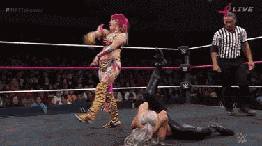 two women are wrestling in a ring while a referee looks on ..