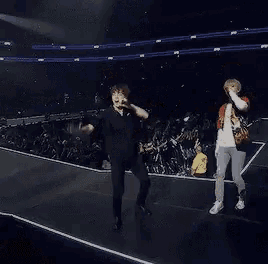 two men are dancing on a stage in front of a crowd of people .