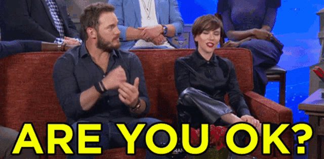 a man and a woman are sitting on a couch with the words " are you ok " written in yellow