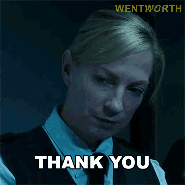 a woman in a suit and tie says thank you in a dark room