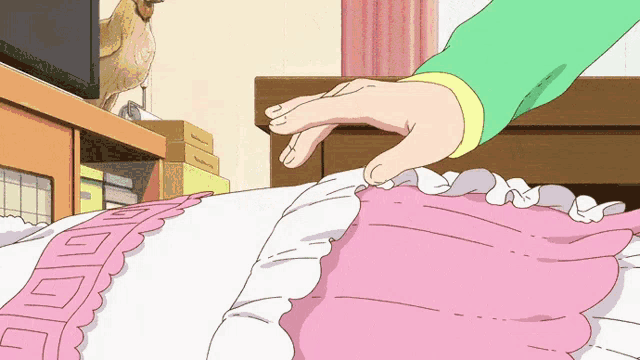 a person 's hand is reaching for a pink and white pillow