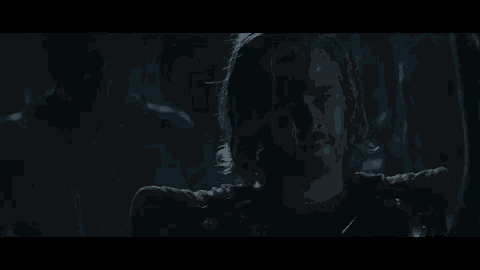 a close up of a person 's face in a dark room with smoke coming out of it .