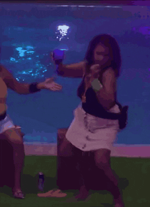 a woman in a black top and white shorts is dancing in front of a swimming pool