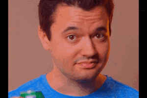 a man in a blue shirt is holding a green can of soda and making a funny face .