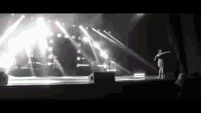 a black and white photo of a woman dancing on a stage in front of a crowd .