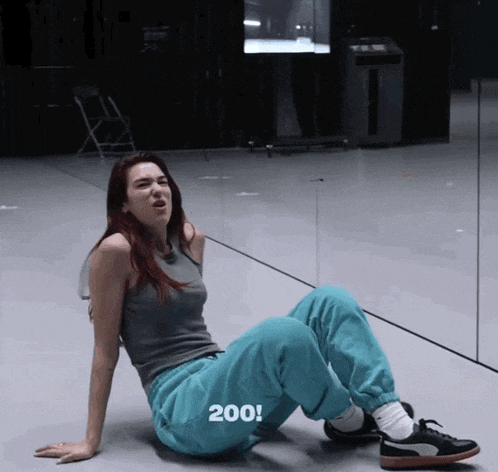a woman is sitting on the floor with the number 200 written on her pants