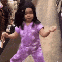 a little girl in a purple outfit is dancing .
