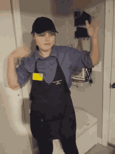 a woman wearing a black apron and a blue shirt with a name tag that says ' jessica ' on it