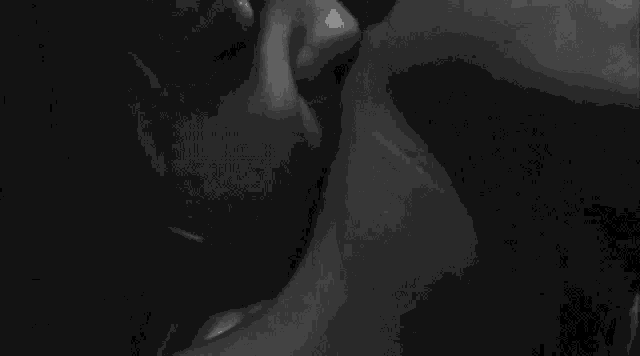a black and white photo of a woman smoking a cigarette in a dark room .
